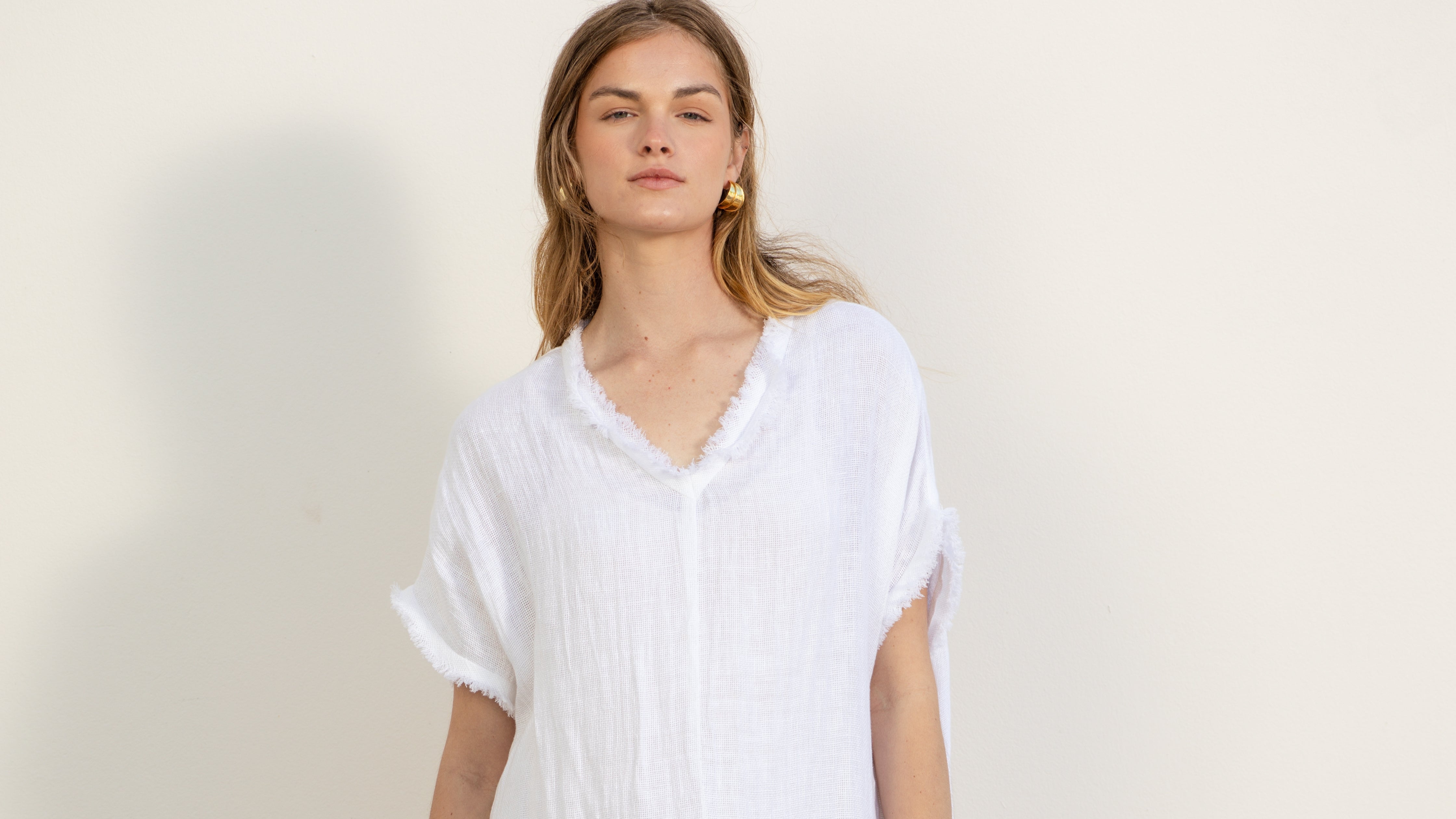 Woman wearing a white becasa fringe maxi against a plain background