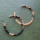 Hoop earrings with black and white pattern on a green surface