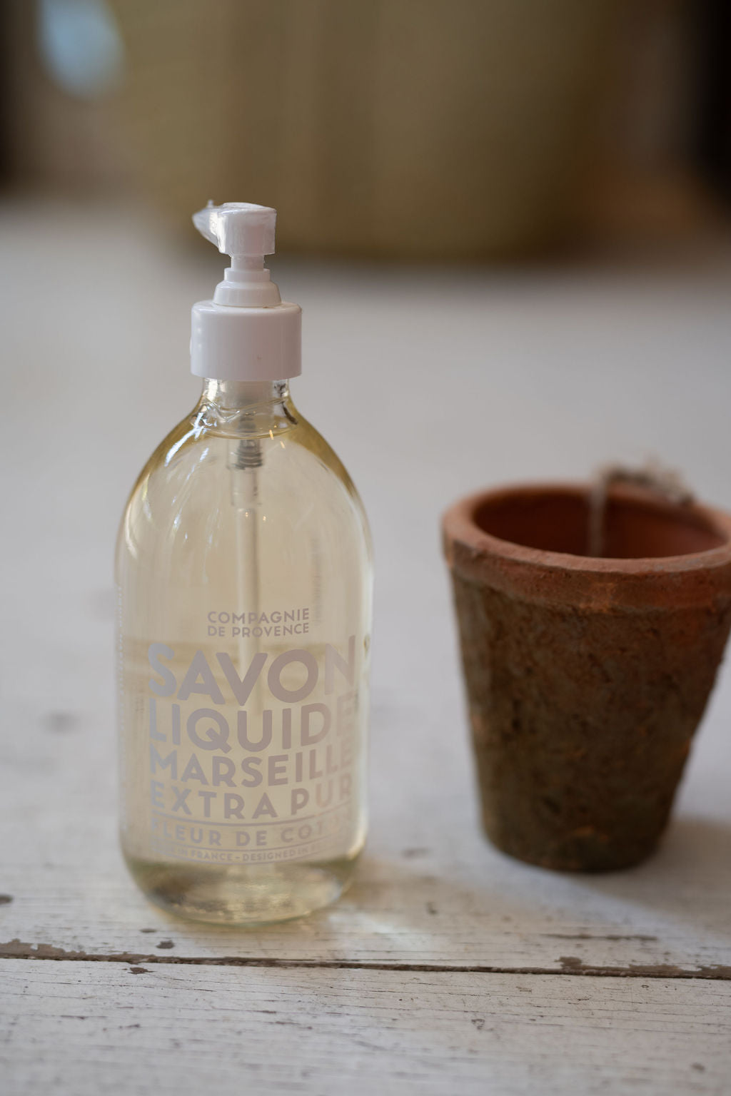 Bottle of Savon Liquid on a wooden surface with a blurred background
