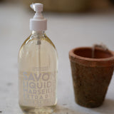 Bottle of Savon Liquid on a wooden surface with a blurred background