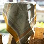 Fabric with a floral pattern draped over a woven basket on a table.