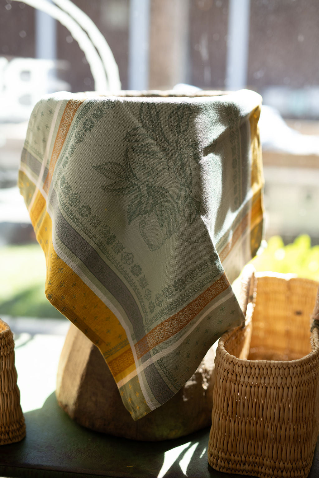 Fabric with a floral pattern draped over a woven basket on a table.
