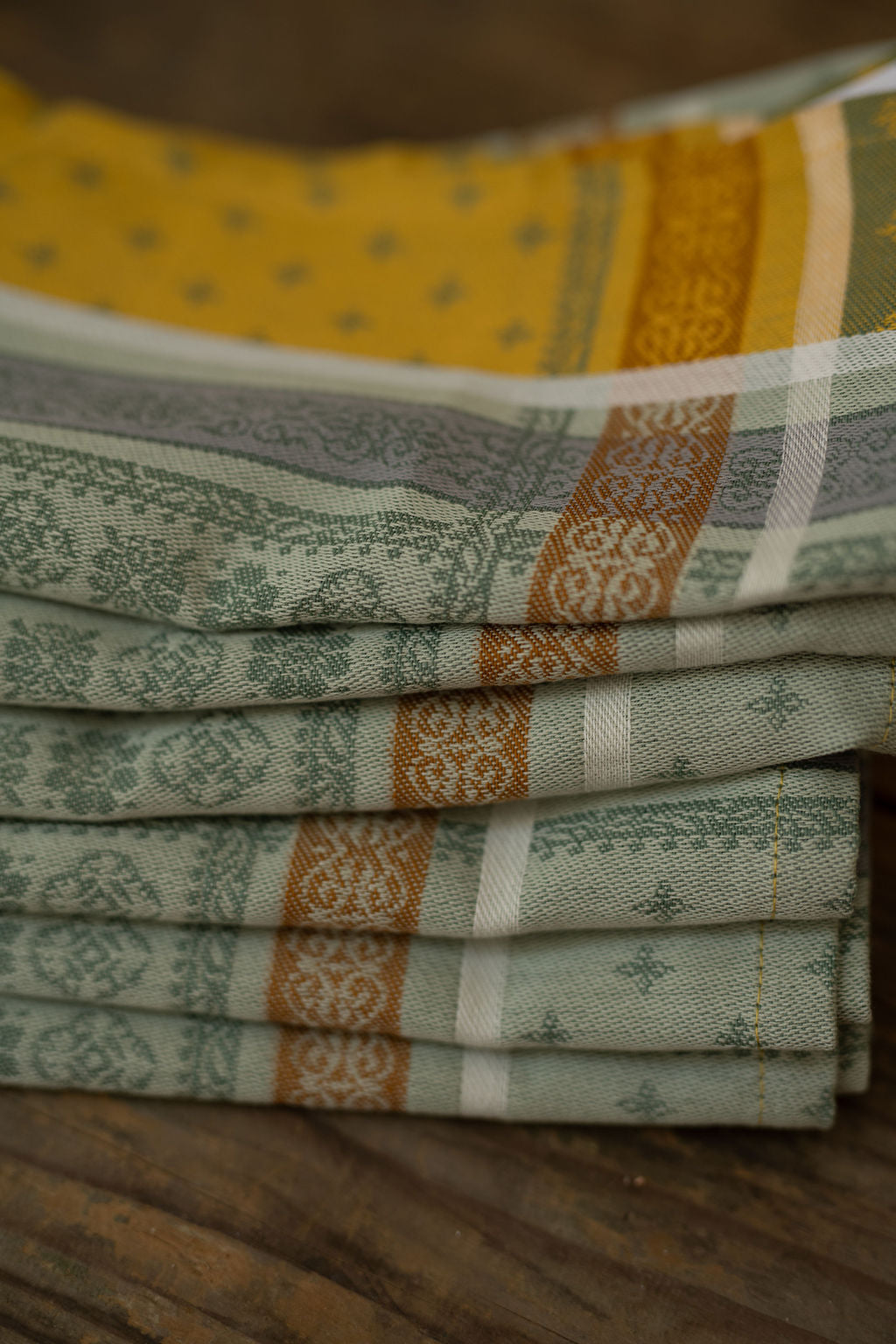 Stack of folded patterned cloths on a wooden surface