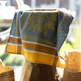 Decorative towel with sunflower pattern draped over a wooden stool outdoors.