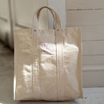Beige tote bag on a wooden floor with a neutral background