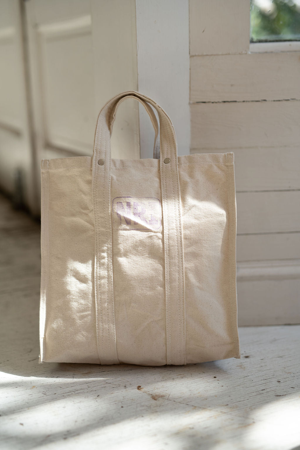 Beige tote bag on a wooden floor with a neutral background