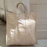 Beige tote bag on a wooden floor with a neutral background