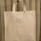 Beige tote bag hanging against a striped background