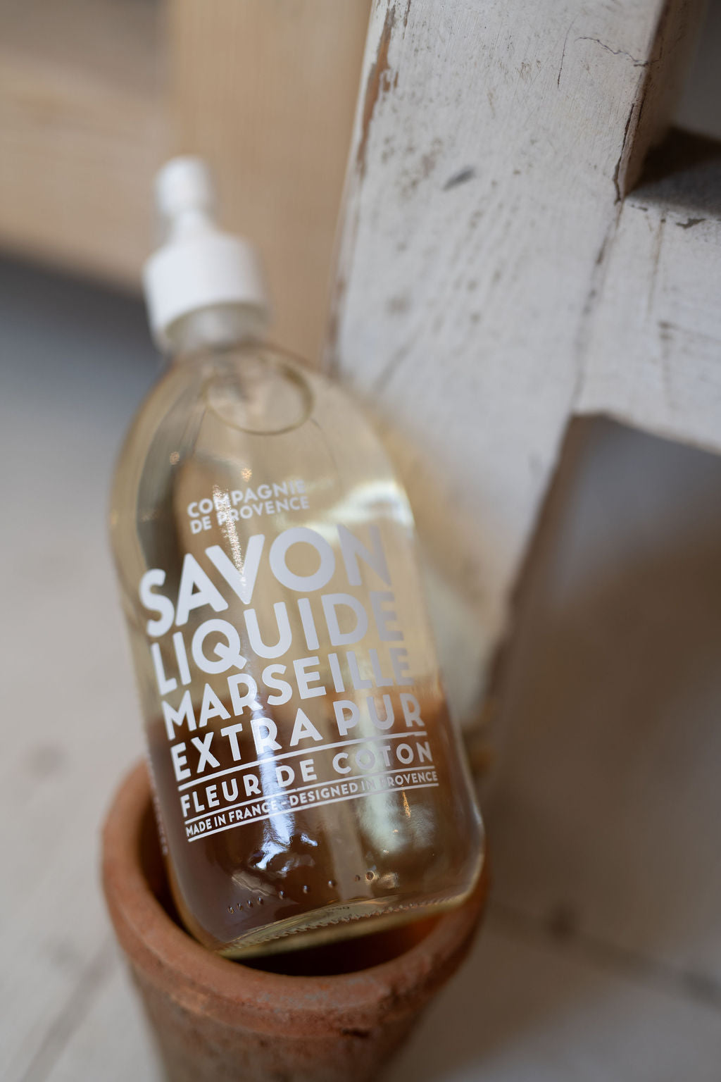 Bottle of Savon Liquide Marseillais Extra Pur on a wooden stand with a blurred background