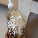Bottle of Savon Liquide Marseillais Extra Pur on a wooden stand with a blurred background