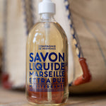 Bottle of Compagnie de Provence Marseille Liquid Soap on a wooden surface with a blurred background.