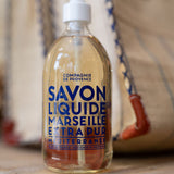 Bottle of Compagnie de Provence Marseille Liquid Soap on a wooden surface with a blurred background.