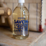 Bottle of Marseille liquid soap on a wooden surface with a blurred background