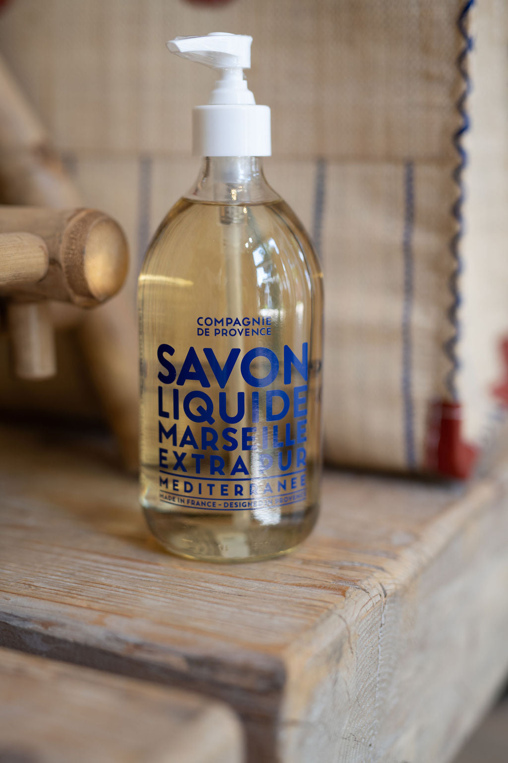 Bottle of Marseille liquid soap on a wooden surface with a blurred background