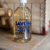 Bottle of Marseille liquid soap on a wooden surface with a blurred background