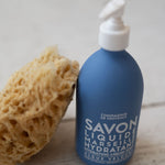 Blue bottle with pump and sponge on a wooden surface