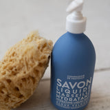 Blue bottle with pump and sponge on a wooden surface