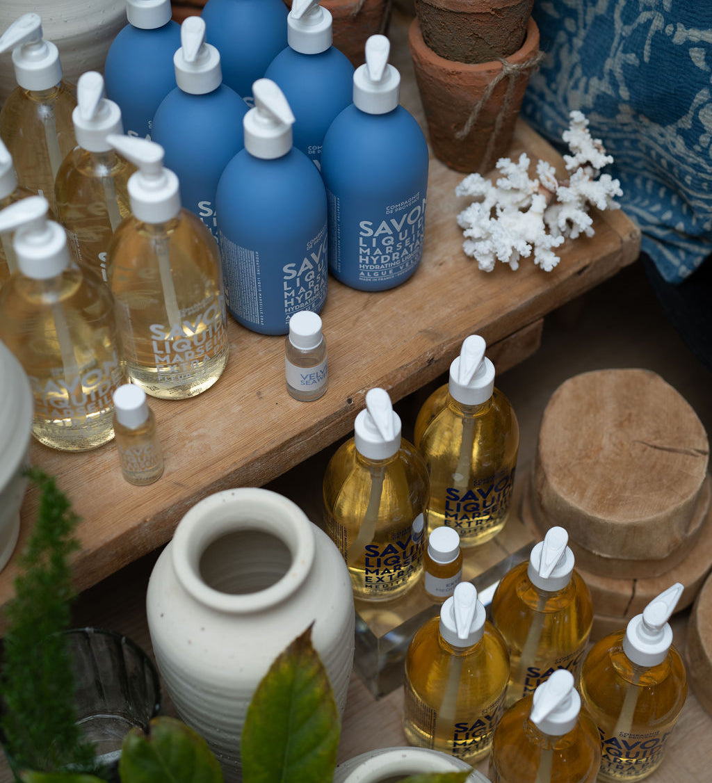 Marseille bottles on a wooden surface with pots and plants.