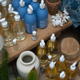 Marseille bottles on a wooden surface with pots and plants.