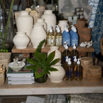 Display of various bottles and containers on a wooden shelf with a neutral background
