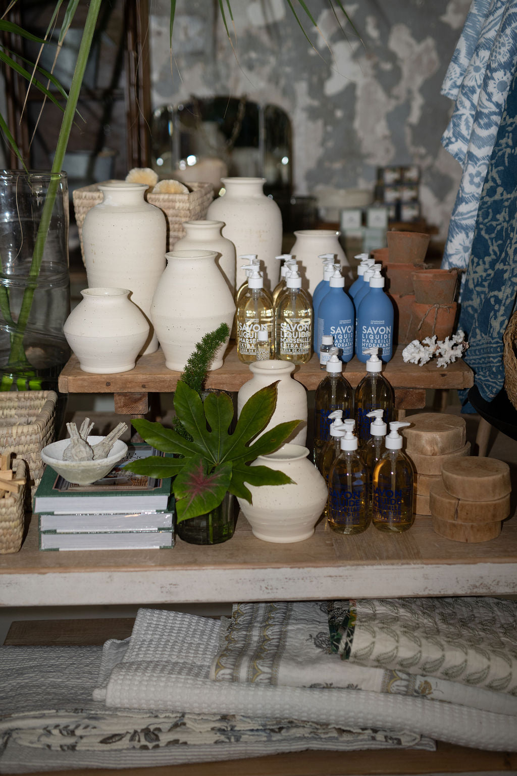 Display of various bottles and containers on a wooden shelf with a neutral background