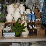 Display of various bottles and containers on a wooden shelf with a neutral background