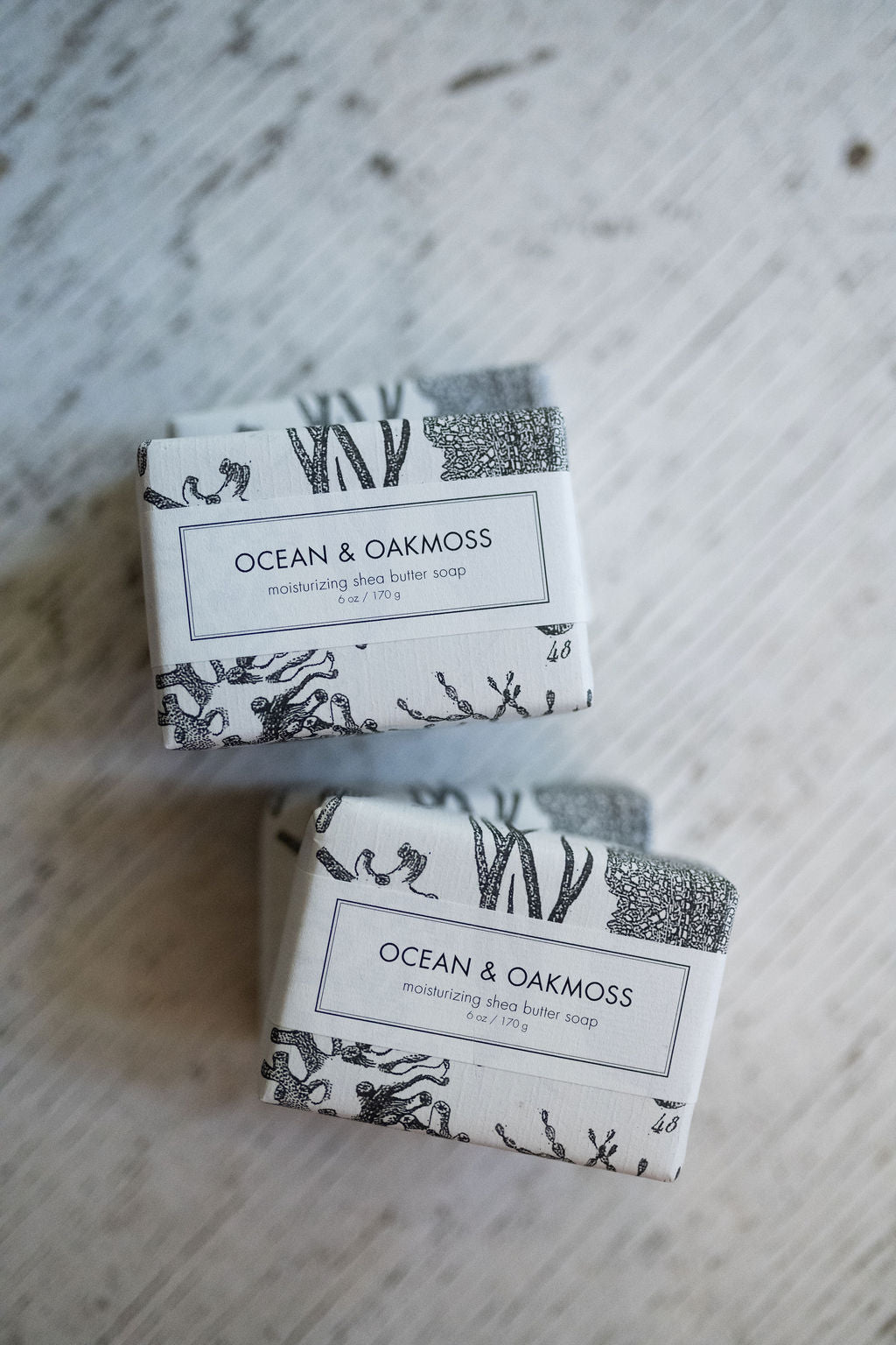 Two bars of soap labeled 'Ocean & Oakmoss' on a textured surface