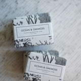 Two bars of soap labeled 'Ocean & Oakmoss' on a textured surface