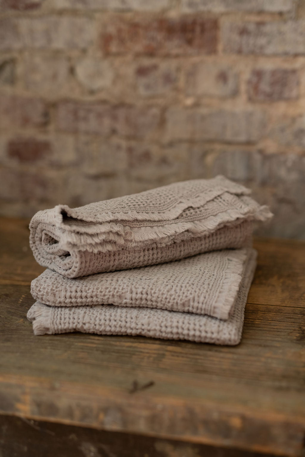 Stack of  towels on a wooden surface with a brick wall background