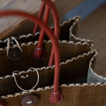 Close-up of a brown leather bag with red handles on a wooden surface