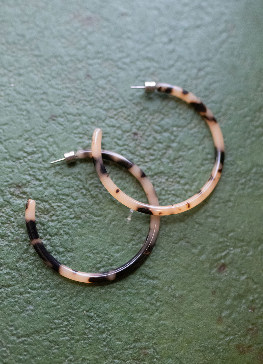 Hoop earrings with black and white pattern on a green surface