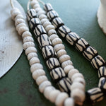 Necklace with white and black beads on a green surface