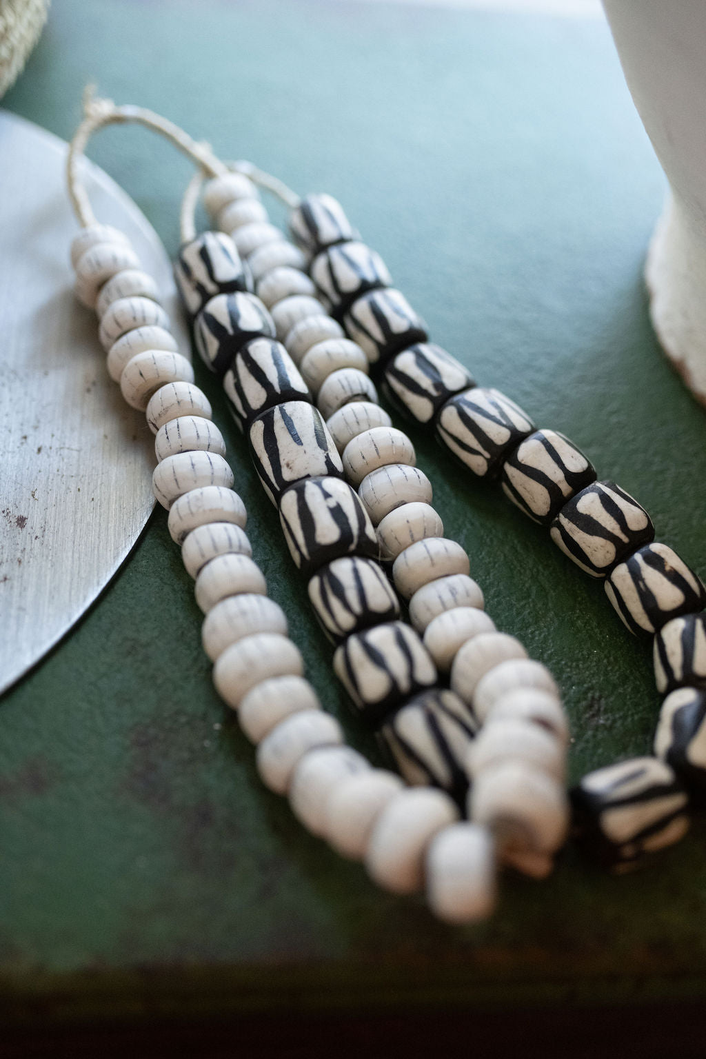 Necklace with white and black beads on a green surface