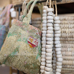 Decorative beaded necklace hanging on a rack with baskets in the background