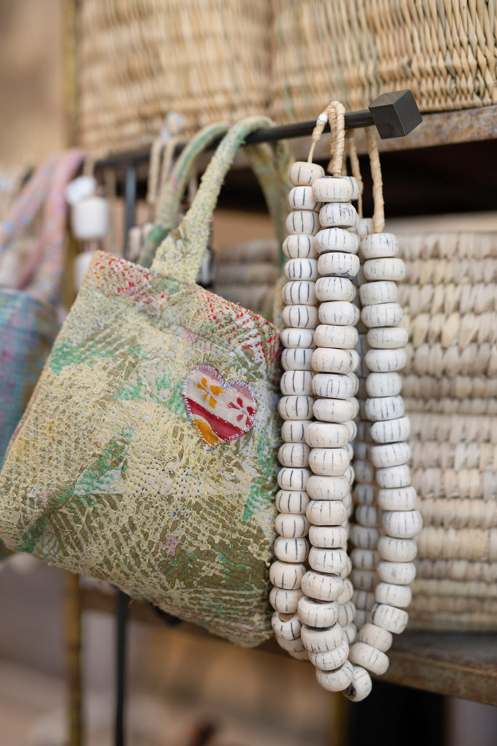 Decorative beaded necklace hanging on a rack with baskets in the background