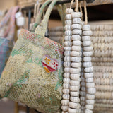 Decorative beaded necklace hanging on a rack with baskets in the background