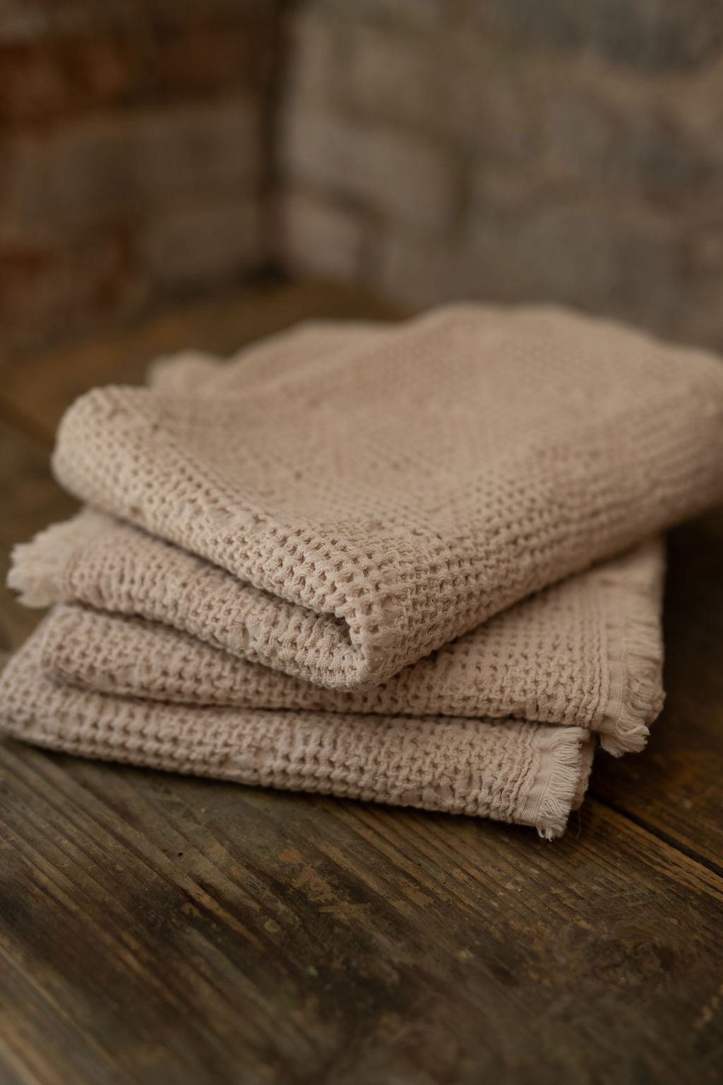 Stack of towels on a wooden surface with a stone wall background