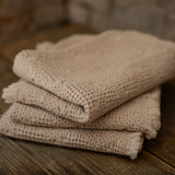 Stack of towels on a wooden surface with a stone wall background